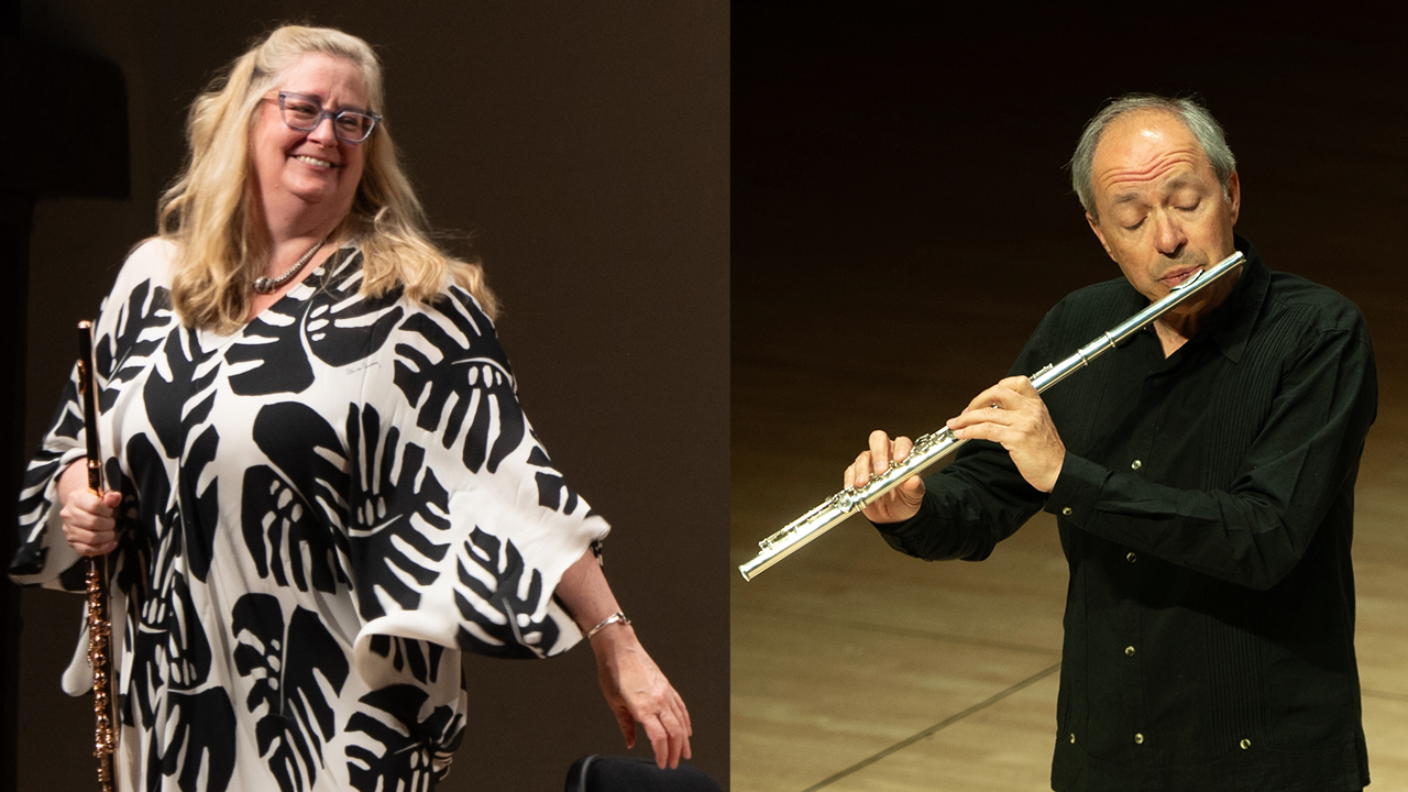 Two flute players on a stage: a smiling woman in a black-and-white patterned poncho on the left, and a man in a black shirt playing a silver flute on the right.